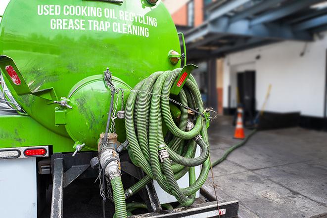 a professional plumber using a pump to empty a grease trap in Bellevue